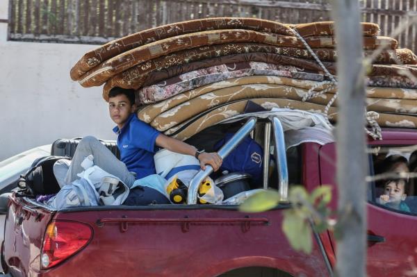 Families crowded into trucks and cars loaded with mattresses, clothing, and possessions.
